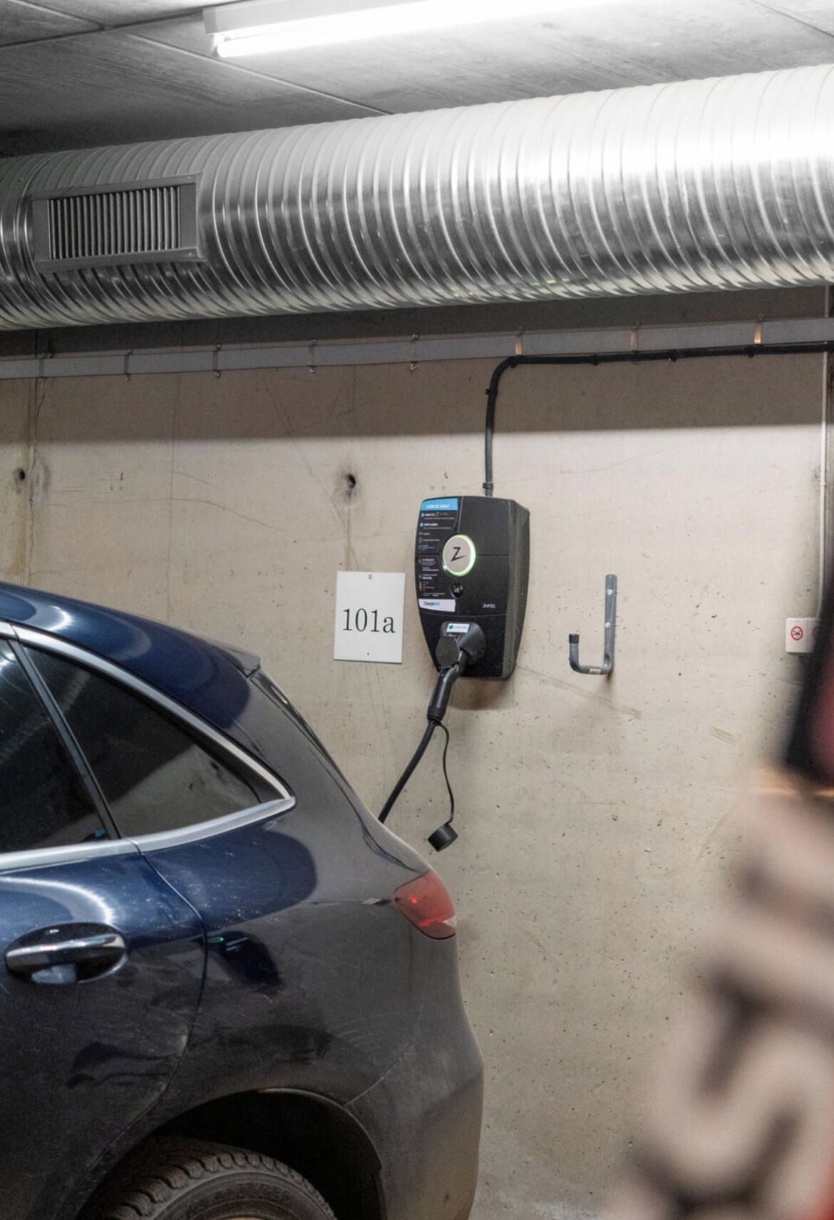 A parking garage with a car parked near a charging station labeled '101a'.