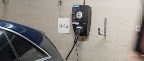 En parkeringskælder med en bil parkeret i nærheden af en ladestation med teksten '101a'.