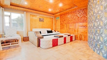 A room with a bed, a white sofa, a small table, and a patterned wall.