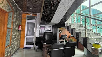 A reception area with a reception desk, black office chairs, a fire extinguisher, and a staircase leading to an upper level.