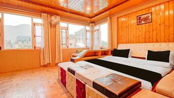 A hotel room with a large bed, a bench, and a view of a mountain.