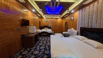A hotel room with wooden paneling, a bed, a desk, a television, and a patterned carpet.