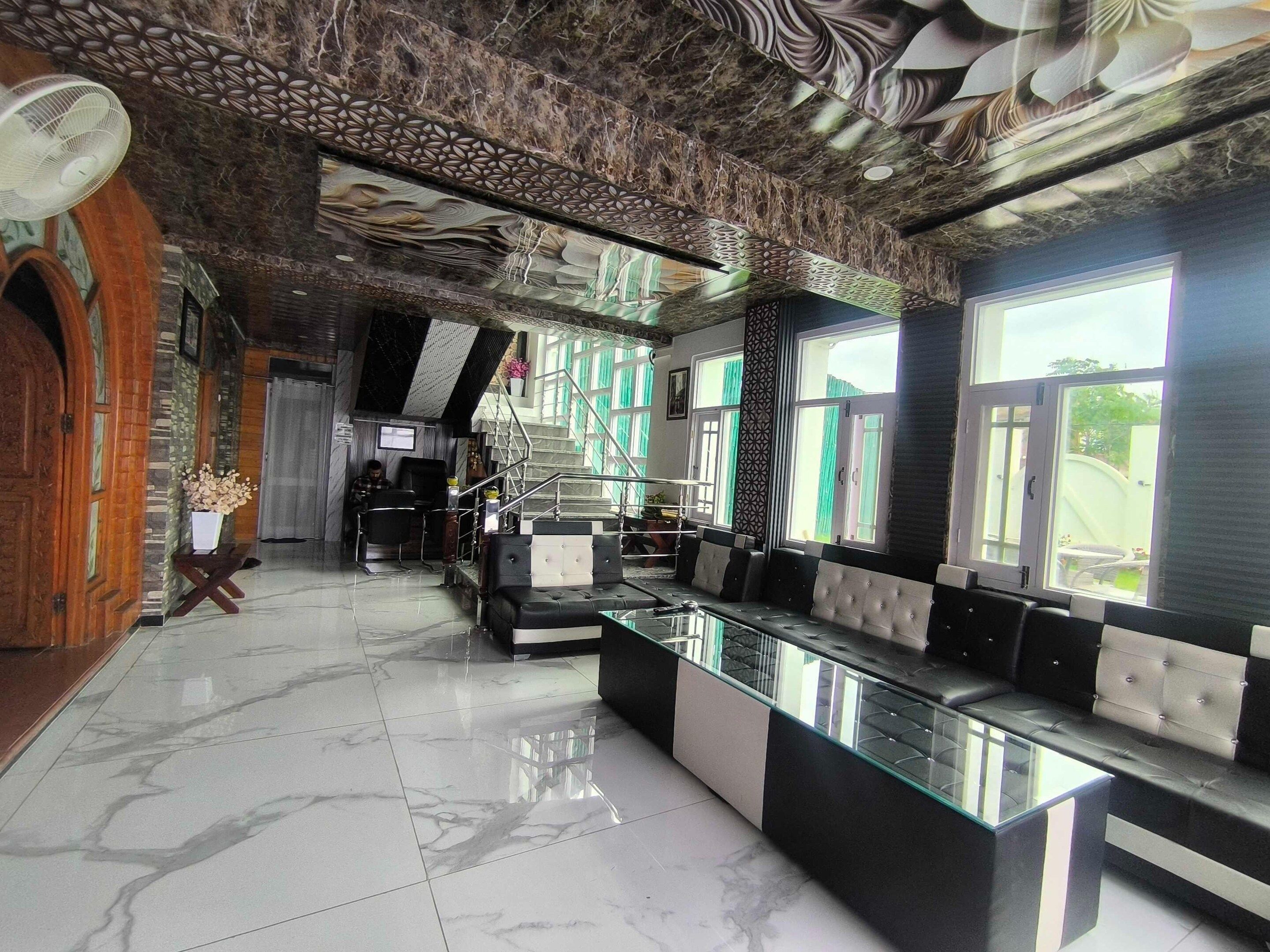 A lobby with a marble floor, a reception desk, a staircase, and seating areas.