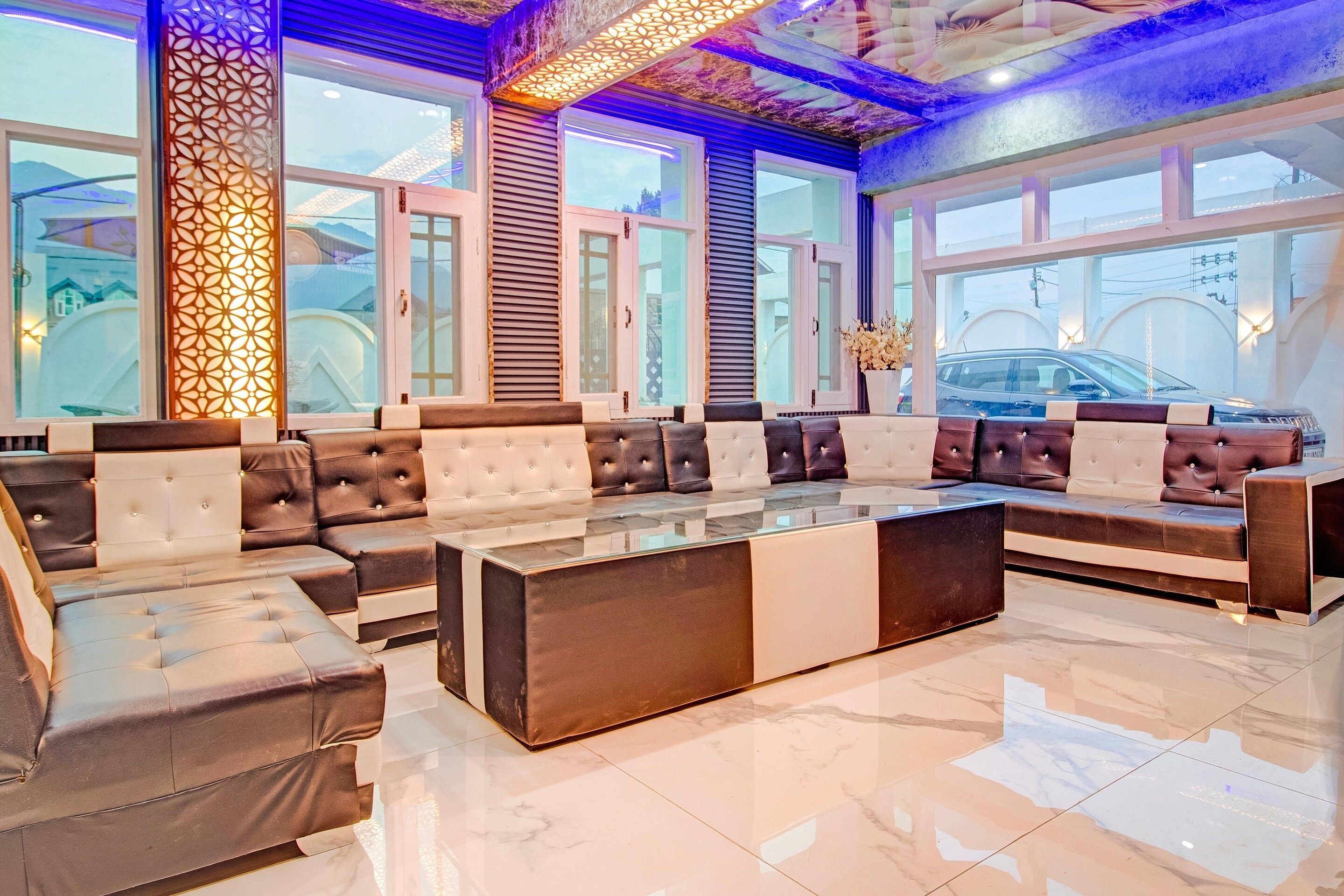 A spacious seating area with a mix of sofas and armchairs, a glass coffee table, and large windows offering a view of the outside.