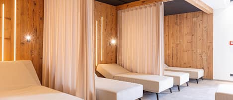 A room with wooden panel walls, a series of beds with white bedding, and a ceiling with exposed beams.