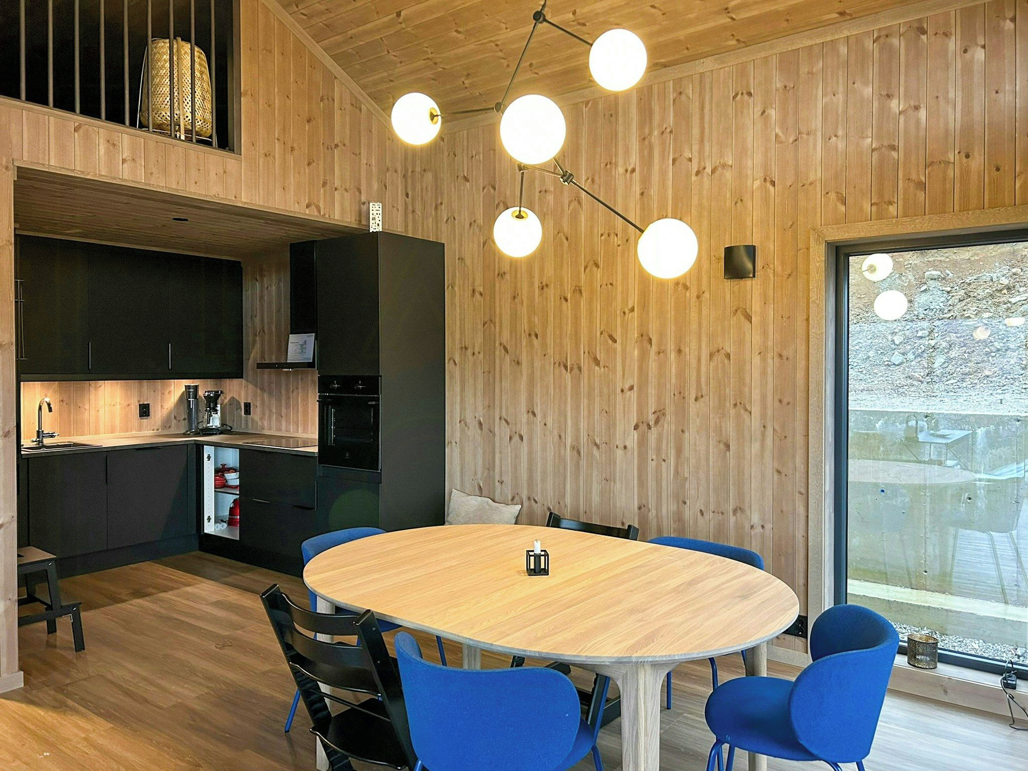 Une cuisine moderne avec des murs en bois, une table ronde et des chaises bleues.