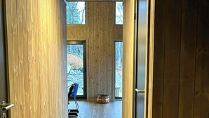 Un couloir aux murs en bois et au sol carrelé mène à une pièce dotée d’une grande fenêtre.