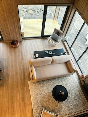 Ein modernes Interieur mit Holzboden, einer Couch, einem kleinen Tisch und einem Sessel.
