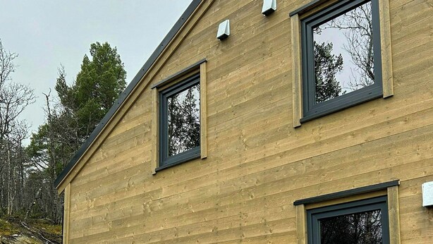 Un bâtiment moderne doté d’une façade en bois, de deux fenêtres et d’une grande porte.