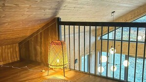 Une pièce avec un plafond en pente, un tapis à motifs, une chaise et une fenêtre donnant sur un beau paysage.