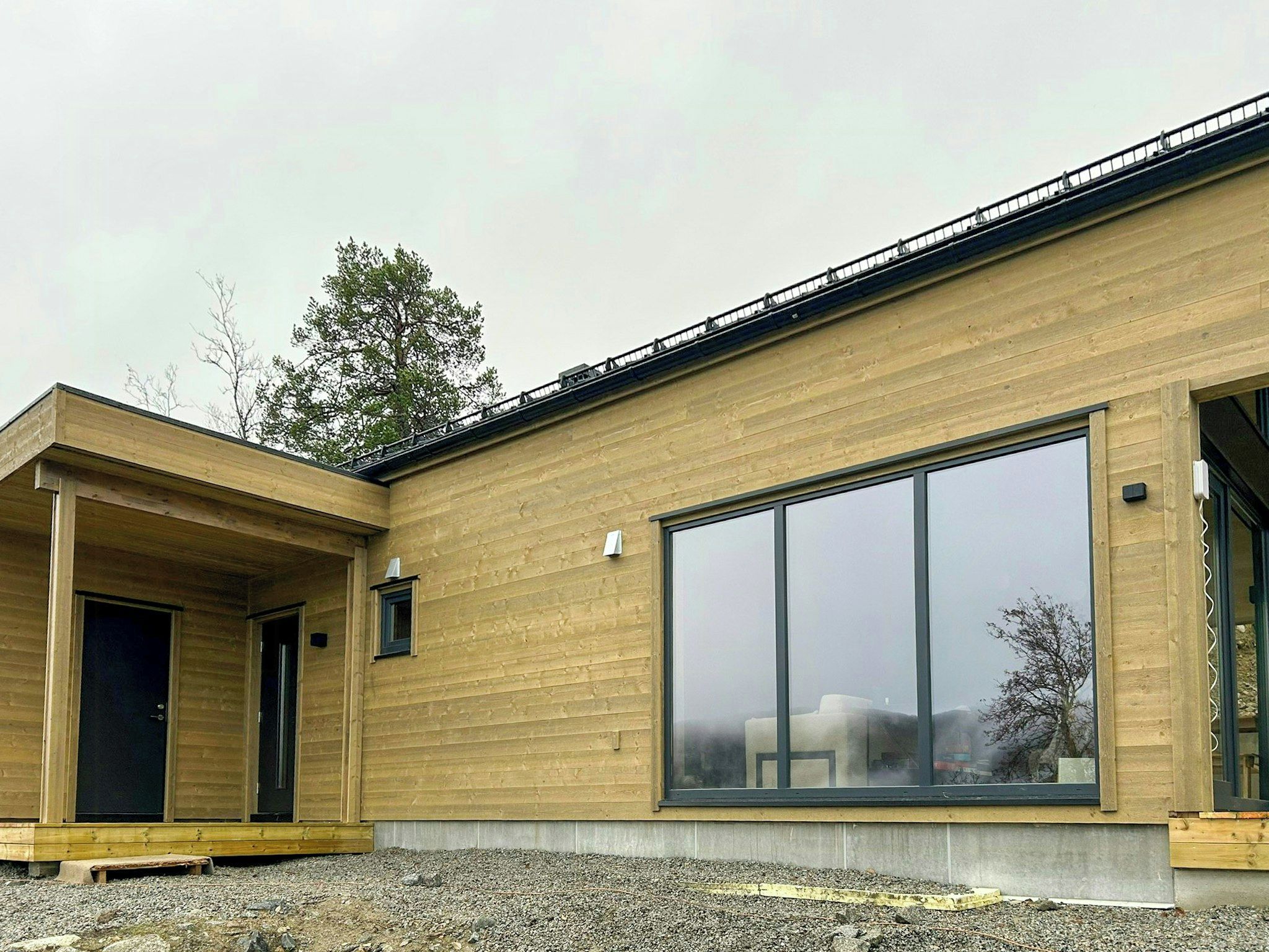 Ein modernes Gebäude mit großen Glasfenstern, Holzverkleidung und einer überdachten Veranda.