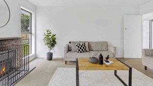 Uma sala de estar moderna com lareira, sofá, mesa de centro e planta em vaso.