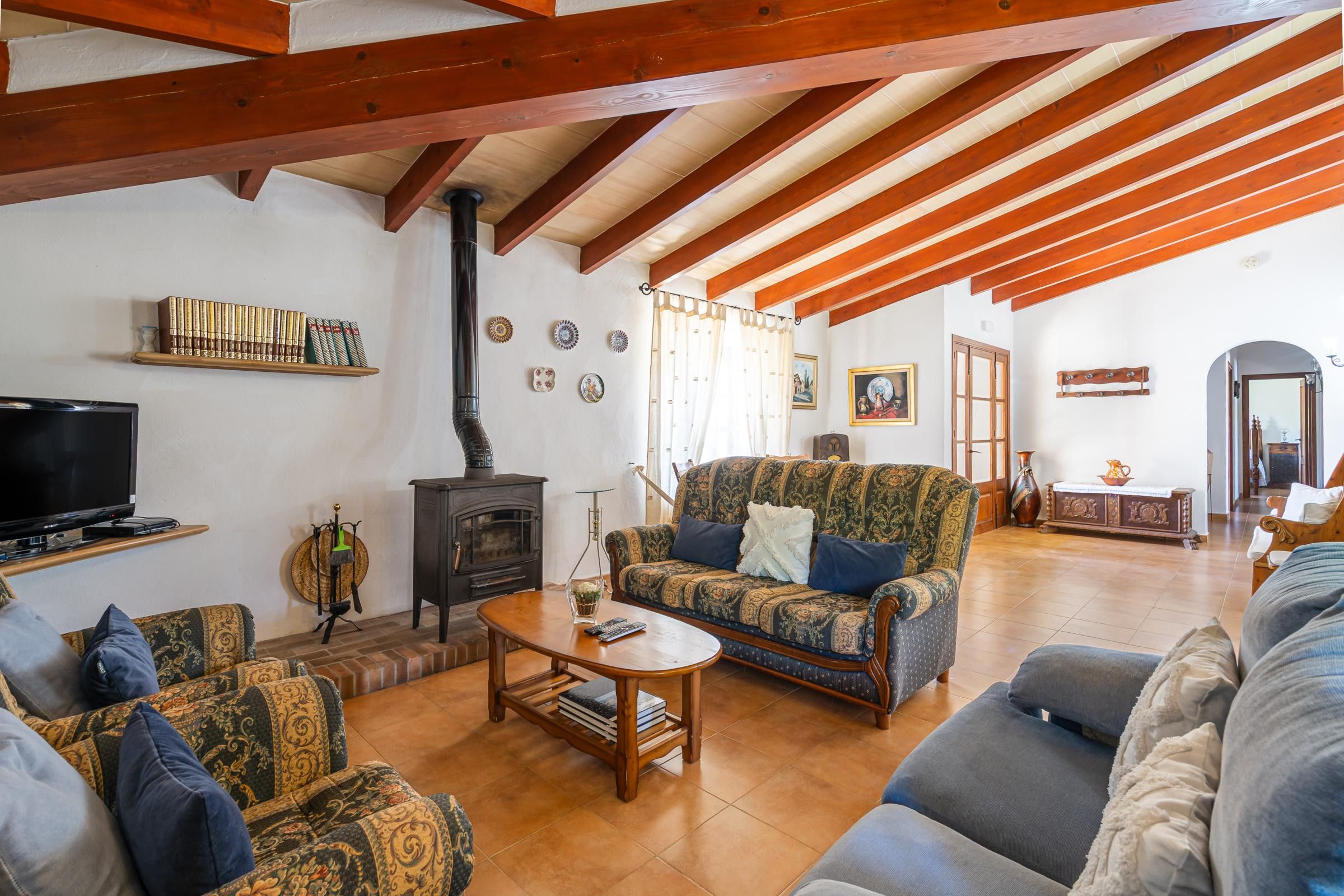 Ein geräumiges Wohnzimmer mit Kamin, Fernseher und Sofa.
