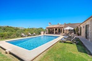 A swimming pool with lounge chairs, a patio area, and a building with a tiled roof. - Villa Malagarba - By Dream Villas Pollensa (Pollensa)