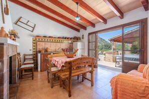 A rustic kitchen with a tiled backsplash, wooden beams, and a dining area with a table and chairs. - Villa Malagarba - By Dream Villas Pollensa (Pollensa)