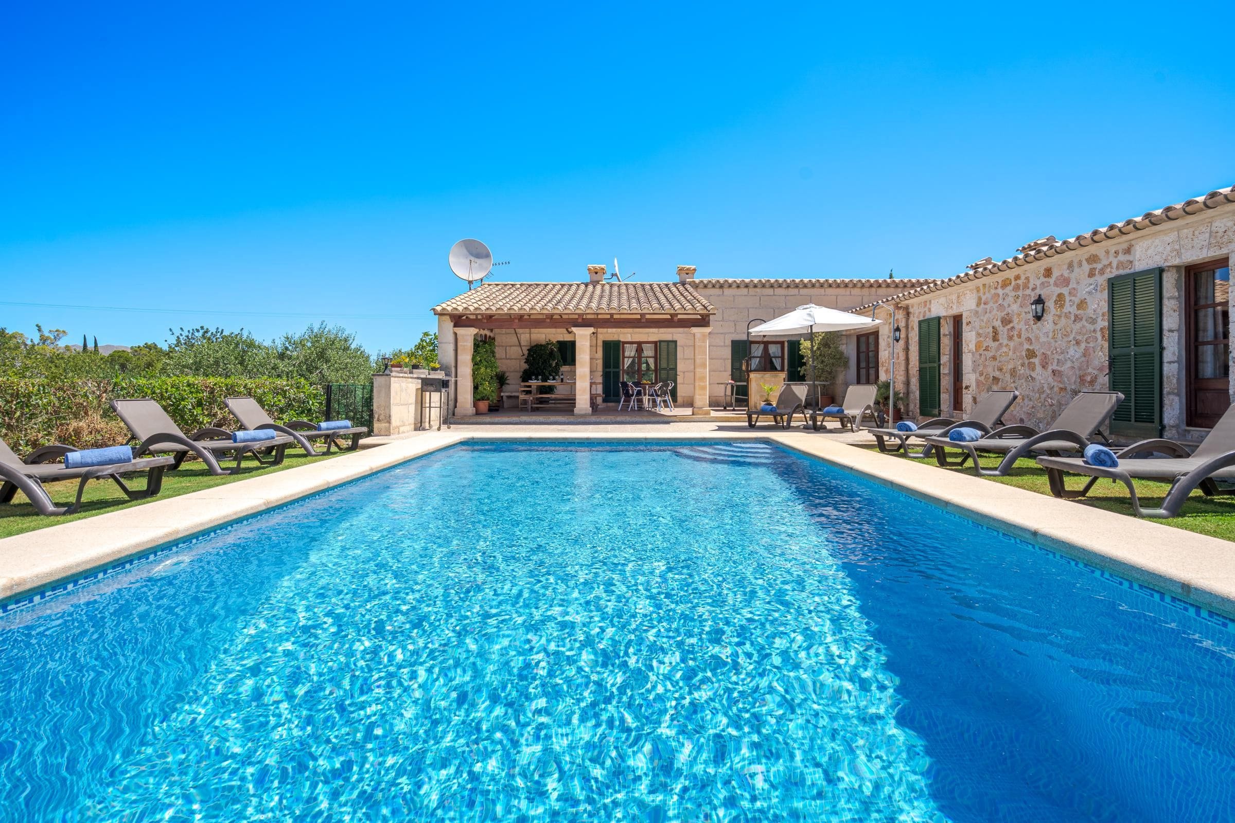 A swimming pool with lounge chairs and a covered patio area.