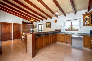 A spacious kitchen with wooden cabinets, a granite countertop, and a built-in dishwasher. - Villa Malagarba - By Dream Villas Pollensa (Pollensa)