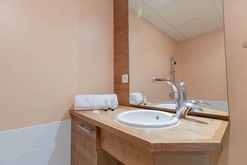 Un baño moderno con tocador de madera, un lavabo blanco y un espejo grande.