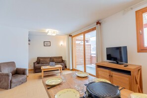 A living room with a sofa, a coffee table, a TV, and a grill. - Super appart confortable ! au pied des pistes (Les Orres)