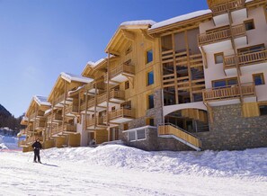 Ein mehrstöckiges Holzgebäude mit Balkonen und einem Steinfundament, umgeben von Schnee.
