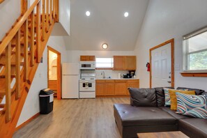 A modern kitchen with wooden cabinets, a built-in oven, and a microwave. There is a staircase leading to an upper level.