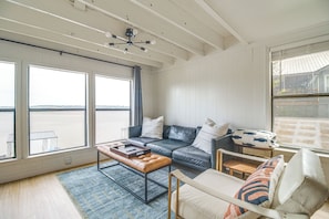 A spacious living room with a large window, a leather sofa, a wooden coffee table, and a view of the water. - Bring Your Boat! Grand Lake Escape w/ Dock (Grove)