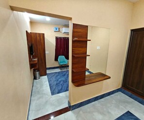 A room with a wooden shelf unit, a blue chair, and a tiled floor with a marble pattern. - Deluxe Pratikshya & Pratistha (Balianta)