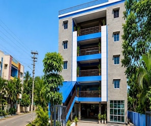 Un edificio de varios pisos con fachada azul y gris, una entrada visible y una escalera que conduce a ella.