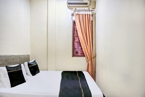 A hotel room with a bed, pillows, a window with curtains, and an air conditioning unit. - Cozy Double Escape W/ Free WiFi and Parking (Medan)