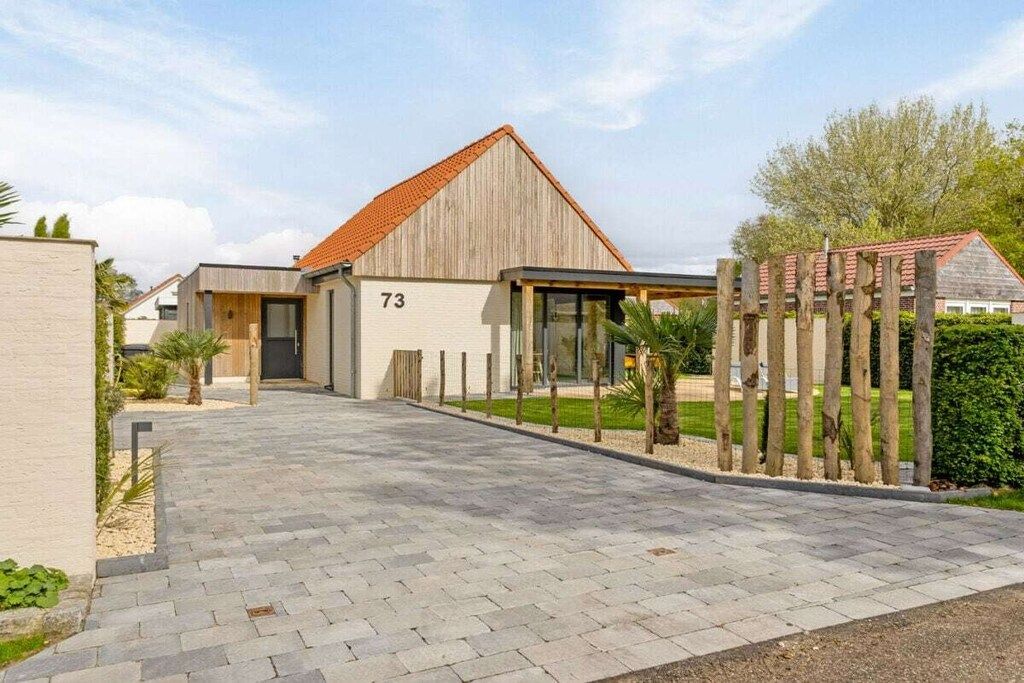 A modern building with a number '73' on the facade, a paved entrance, and a wooden fence.