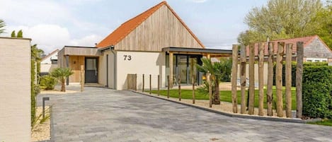 A modern building with a number '73' on the facade, a paved entrance, and a wooden fence.