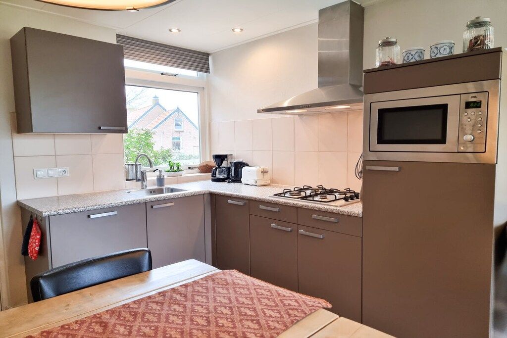 A compact kitchen with a gas stove, microwave, and a window providing a view of the outside.