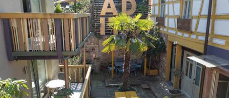 A courtyard with a wooden fence, a palm tree, and outdoor seating.