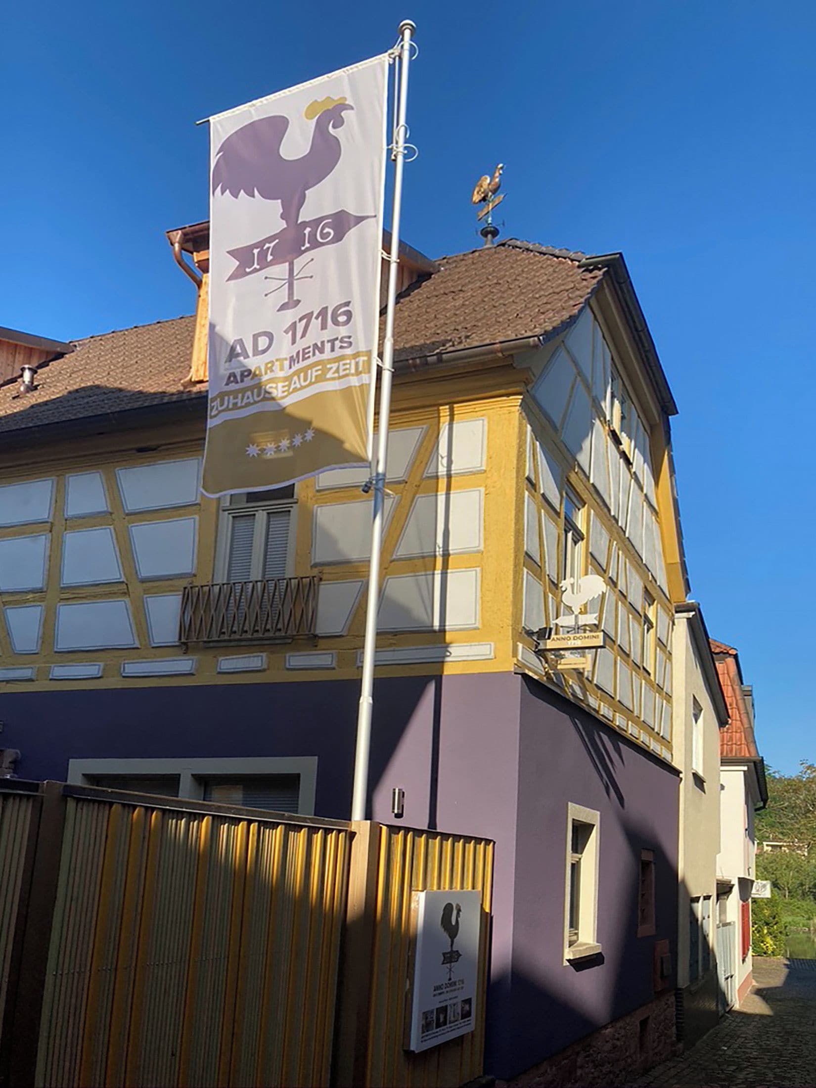 Ein Gebäude mit einer Flagge, die das Jahr 1716 und den Text 'AD 1716 APARTMENTS ZUHAUS AUF ZEIT' zeigt.