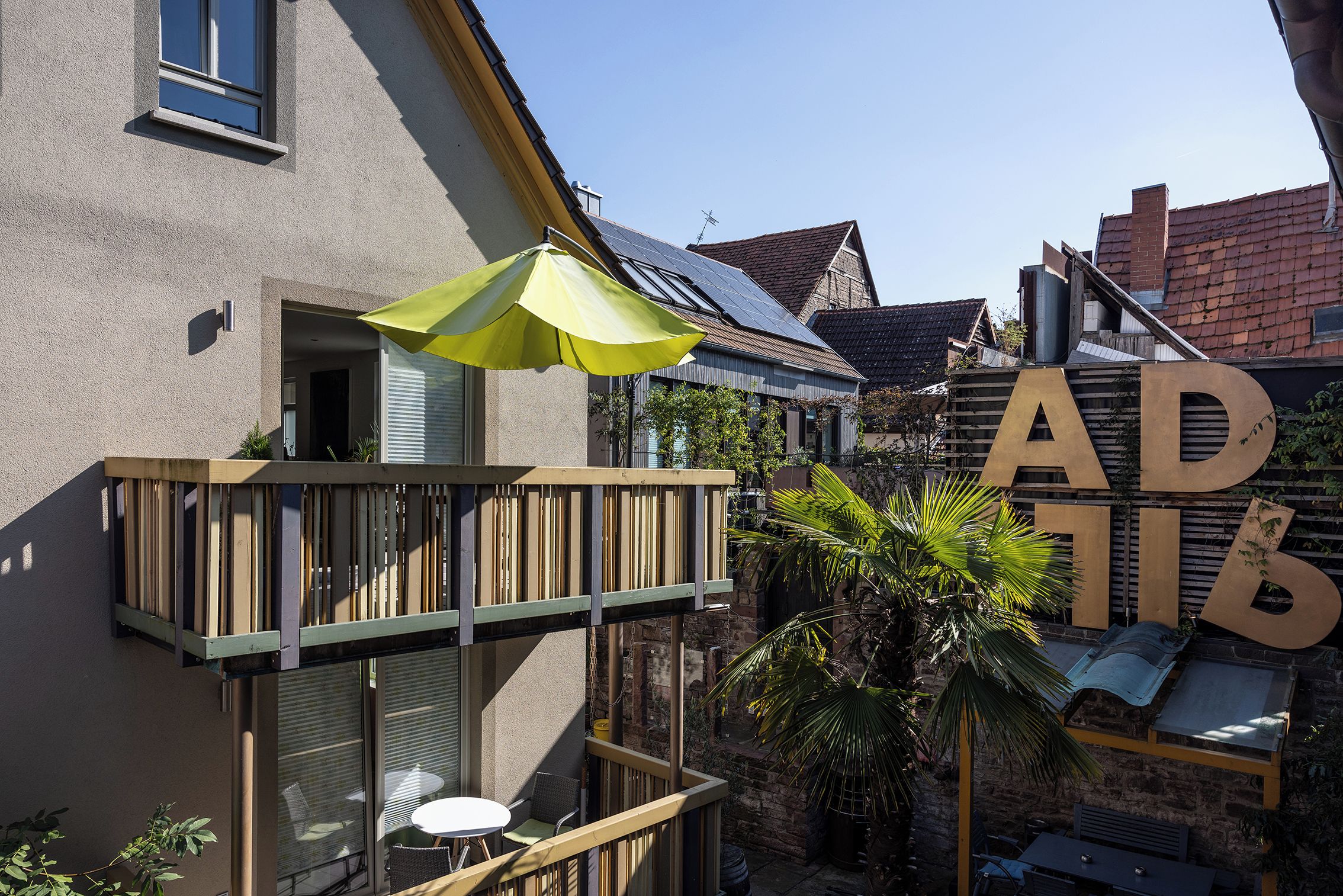 Un immeuble résidentiel doté d’un balcon, d’une table et de chaises, ainsi que d’une grande enseigne avec des lettres.