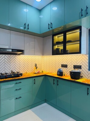 A modern kitchen with teal cabinets, a herringbone tile backsplash, and a gas stove.
