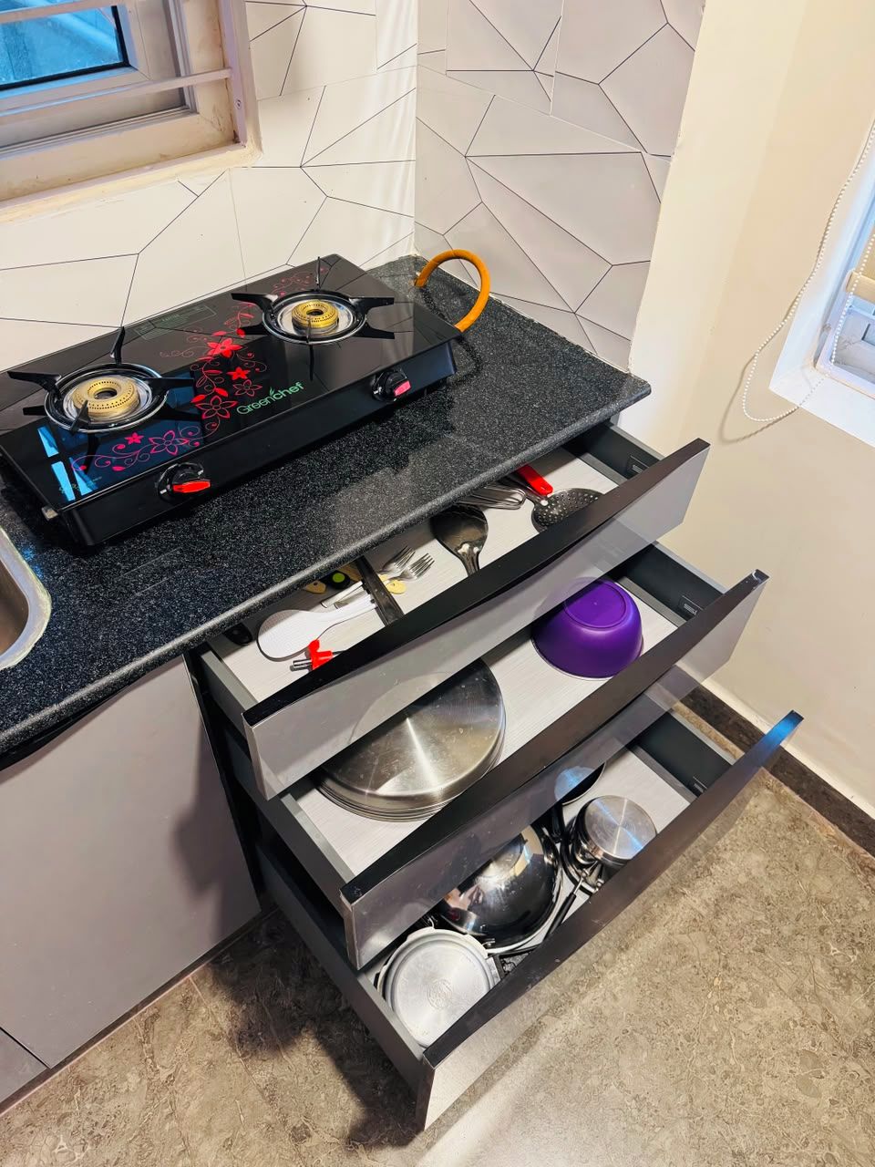 Una cocina con estufa a gas, un cajón con utensilios y una encimera.