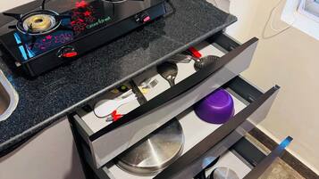 Una cocina con estufa a gas, un cajón con utensilios y una encimera.