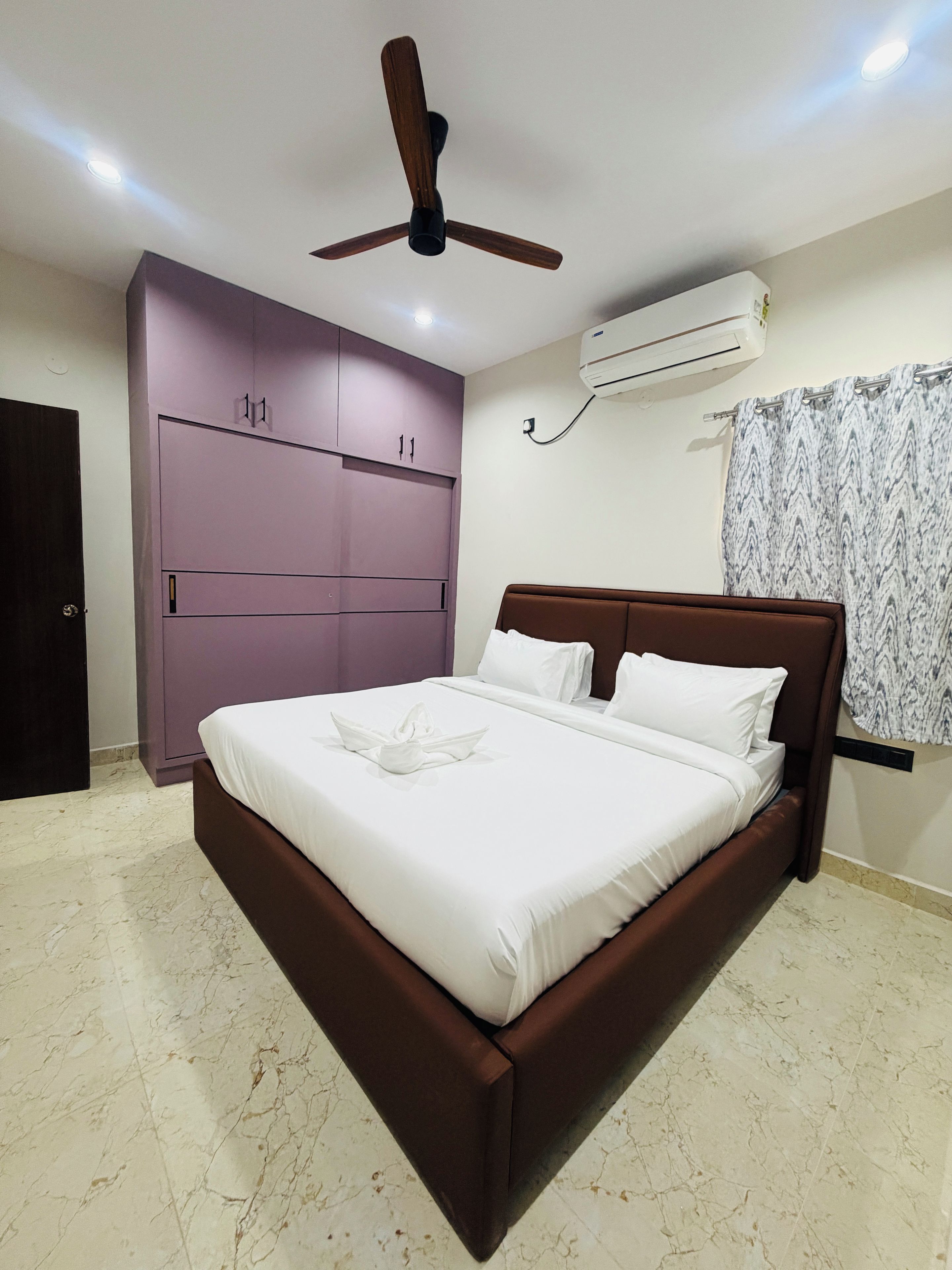 Quarto com cama, ventoinha no teto, ar condicionado e guarda-roupa.