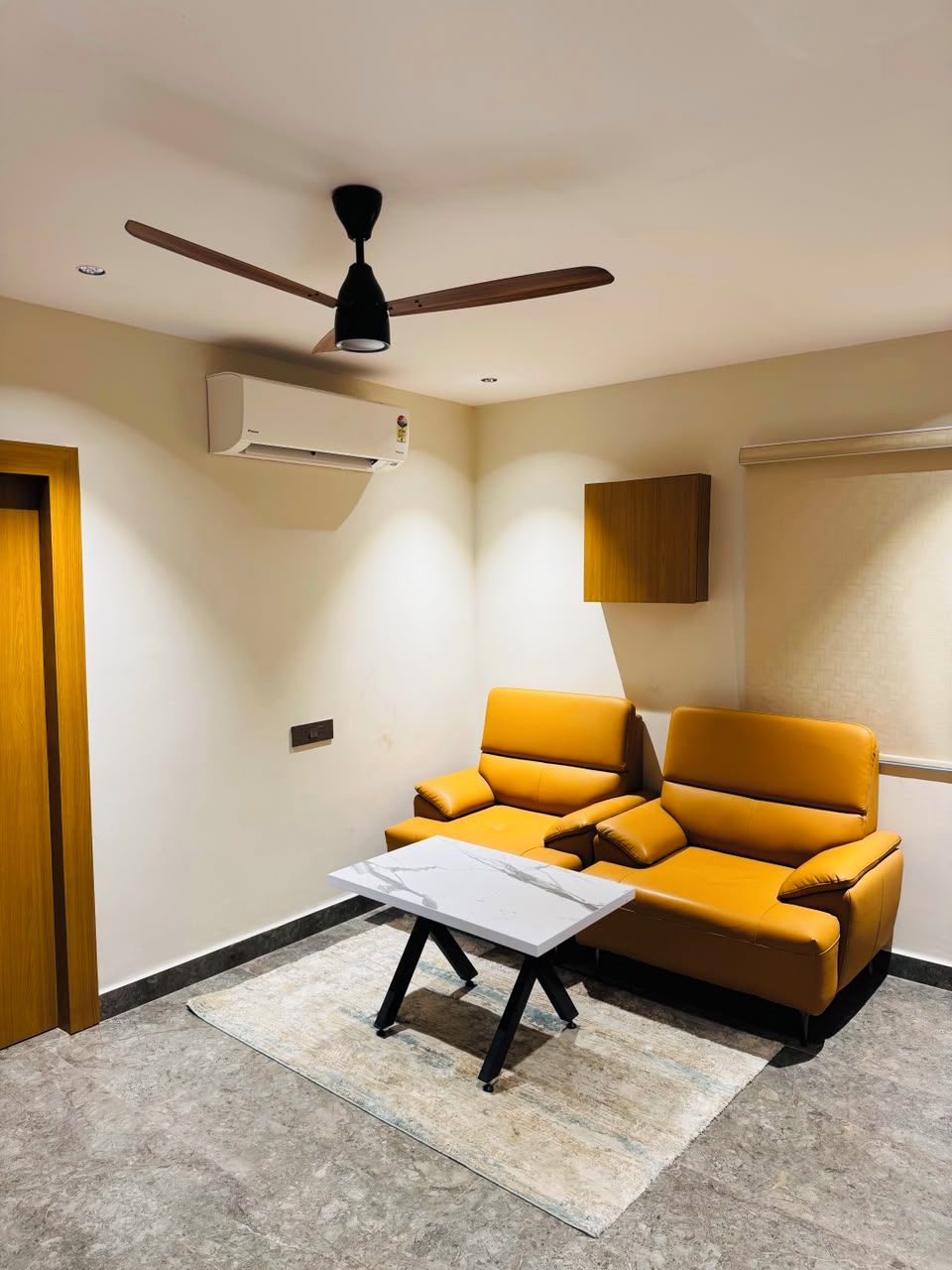 Sala de estar com sofá, mesa de centro, ventilador de teto e ar condicionado.