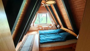 A cozy attic bedroom with a bed, a table, and a chair. - Vrbo Property (Butjadingen)