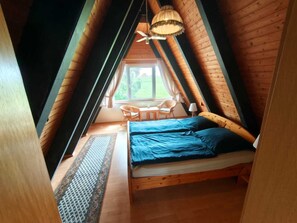 Una camera da letto mansardata accogliente con un letto, un tavolo e una sedia.