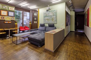 A modern interior with a sectional sofa, a wooden desk, and framed artwork on the walls. - Exclusive Suite in Marktheidenfeld - Modern Comfort Meets Original Art (Marktheidenfeld)