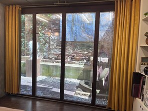 Ein Zimmer mit einer großen Schiebeglasdoor, die zu einem Außenbereich mit einem Felsenbeet und einem kleinen Teich führt.