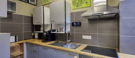 A modern kitchen with a digital clock, stainless steel appliances, and wooden countertops.