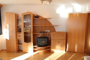 Ett rum med ett träskåp, en tv på ett stativ och en dörr.