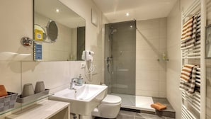 Ein modernes Badezimmer mit einer Duschkabine aus Glas, einem weißen Waschbecken und einer Toilette.