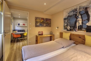 A bedroom with a bed, a desk, a chair, and a painting. - Charming 1-Bedroom Apartment in Historic Marktheidenfeld (Marktheidenfeld)