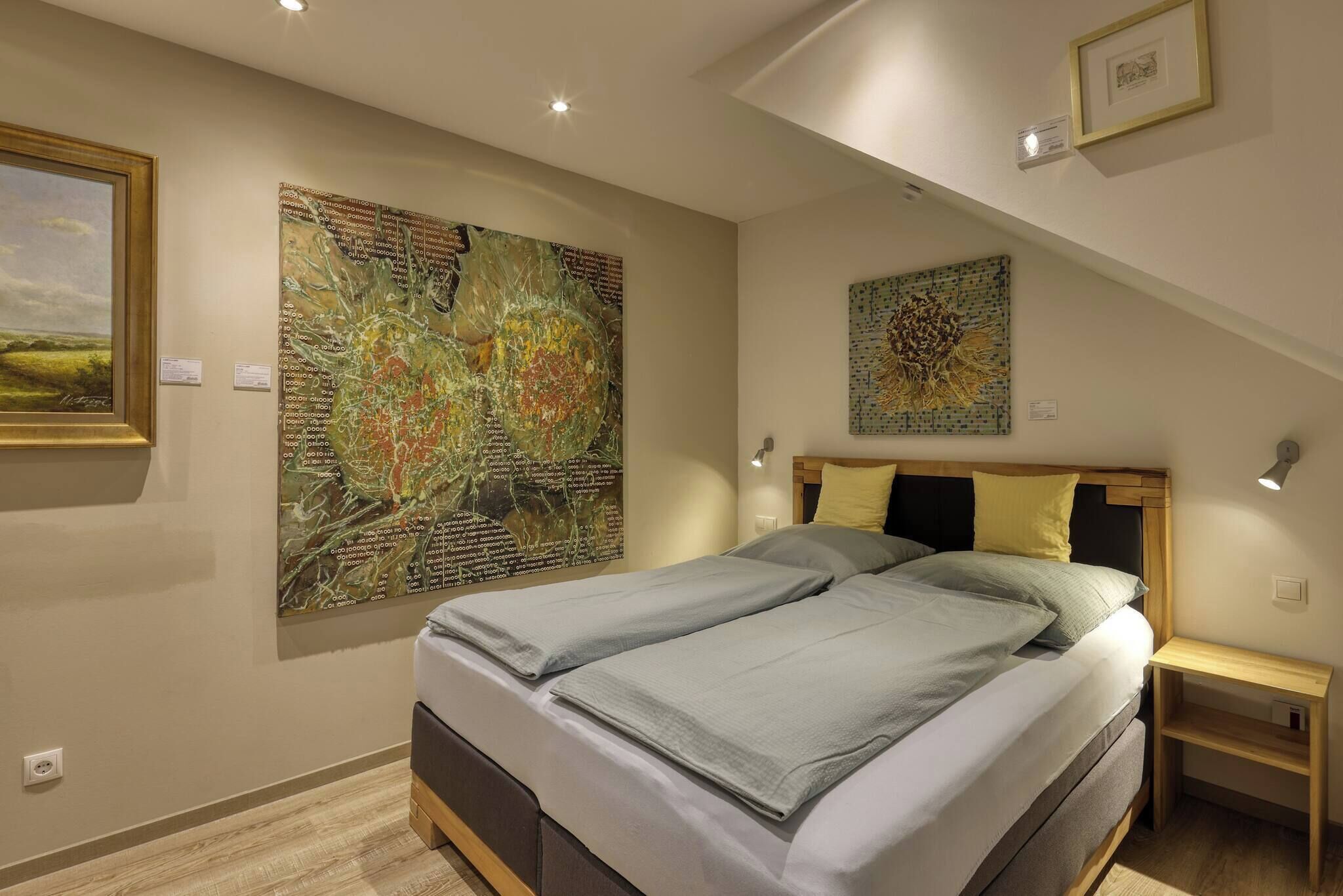 A bedroom with a bed, two bedside tables, and two wall-mounted artworks.