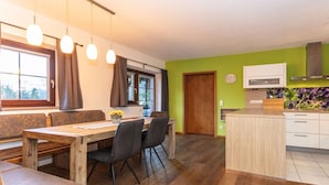 A dining area with a wooden table and chairs, a bench, and a kitchen with a microwave and cabinets. - Holiday apartment in Lofer with swimming pool (Lofer)